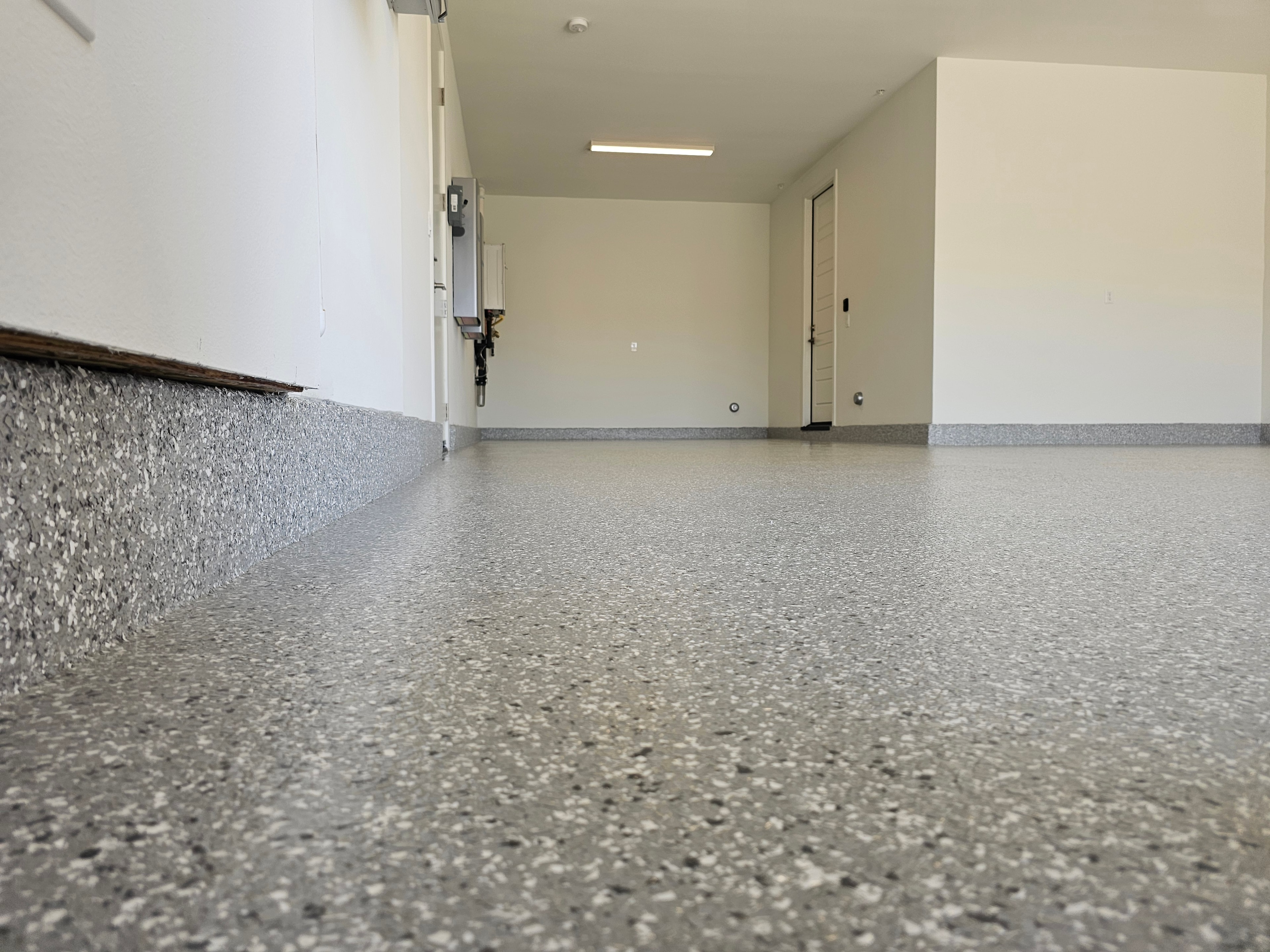 Grey epoxy flake floor in clean empty garage — wide view