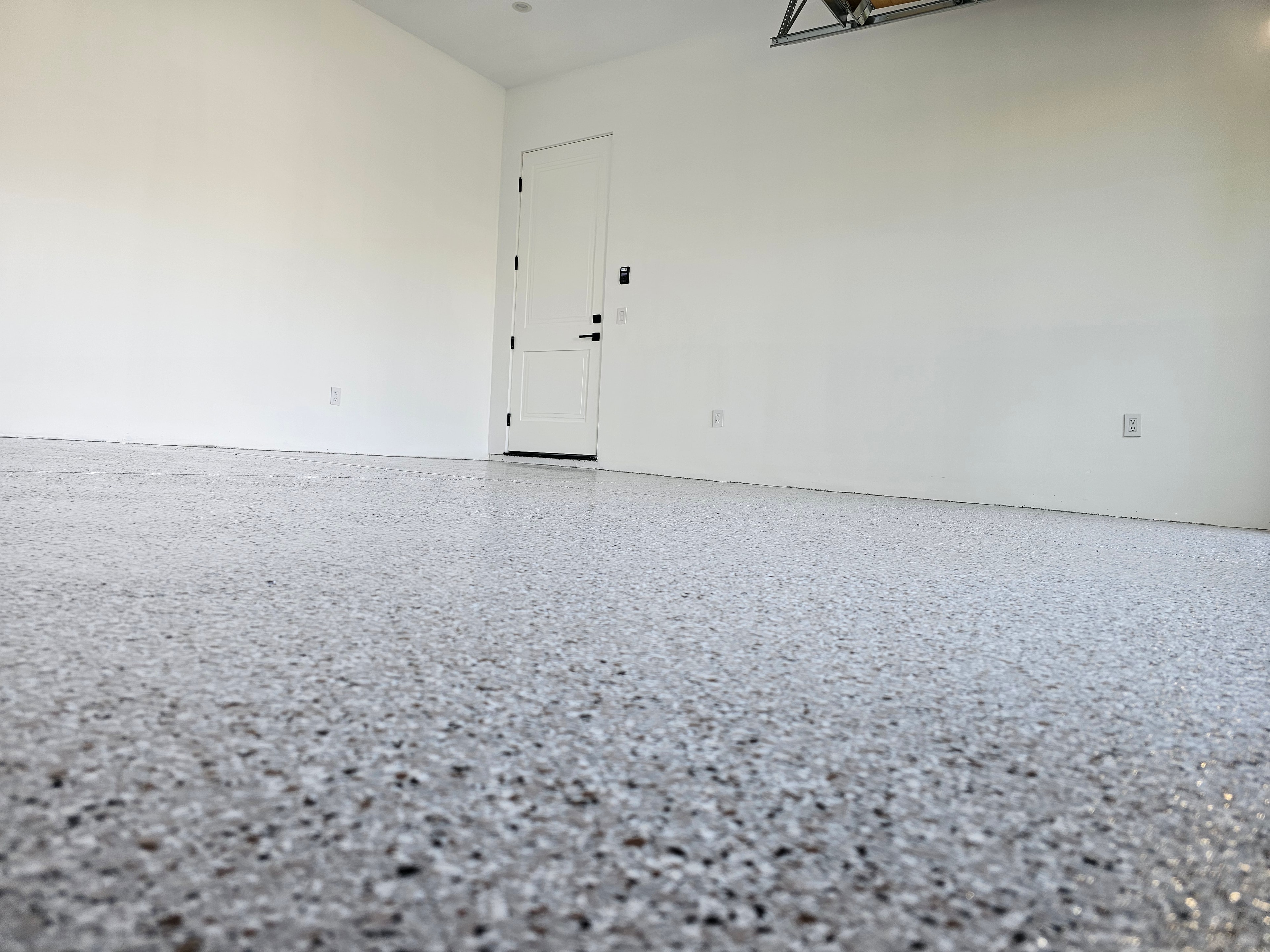 Speckled epoxy garage floor with white walls — close-up floor view